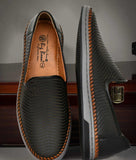 Black men's slip-on loafer shoes with textured synthetic leather and brown stitched detailing on sole edges